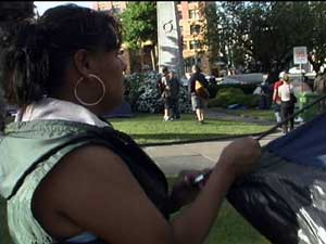 Squatter sets up tent with cenotaph in background